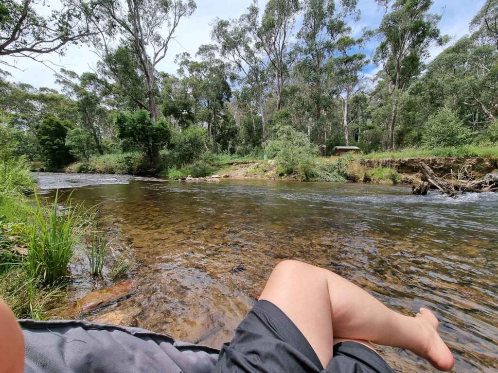 Legs of person in campchair with river in background